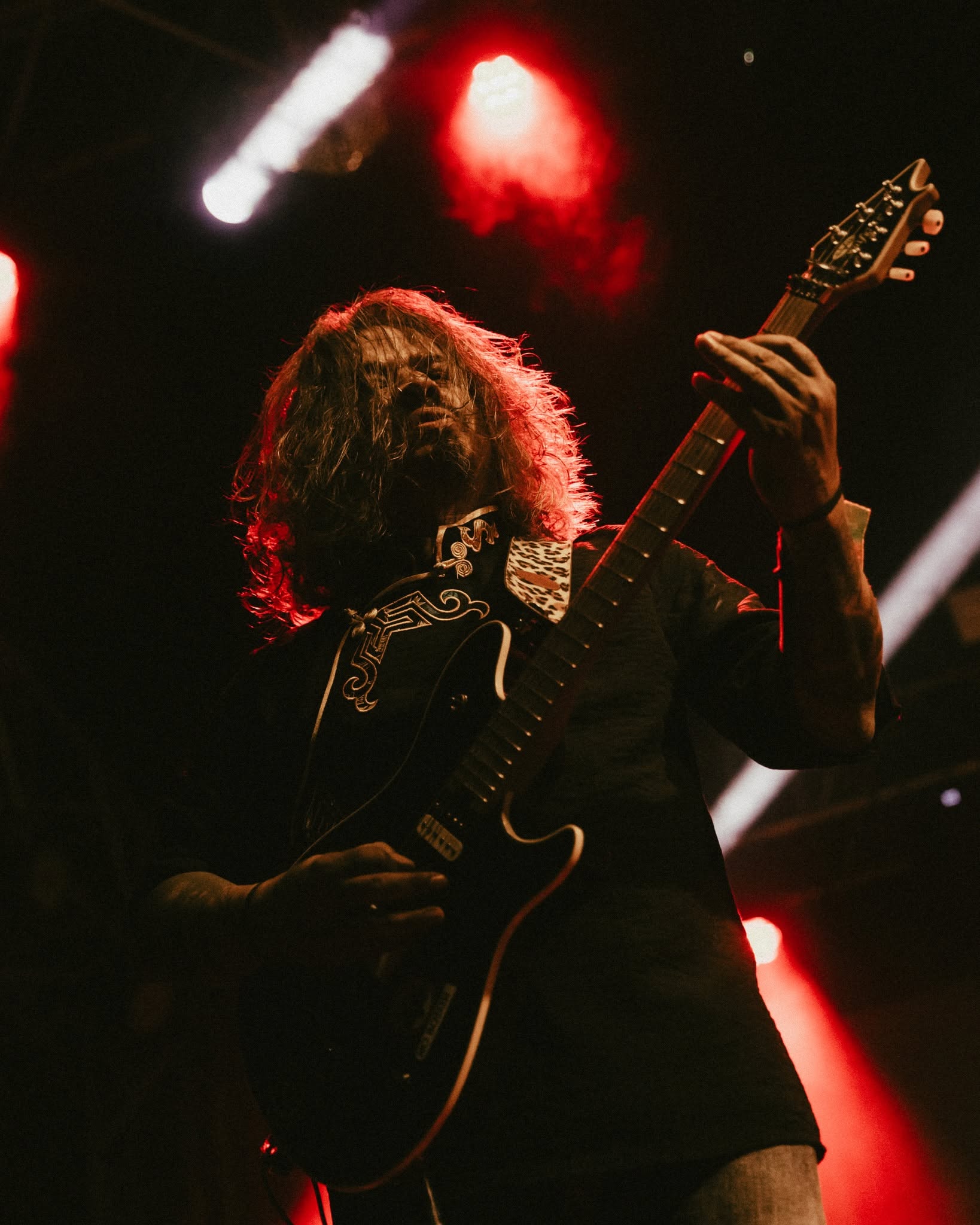 Guitarist performing under red stage lights