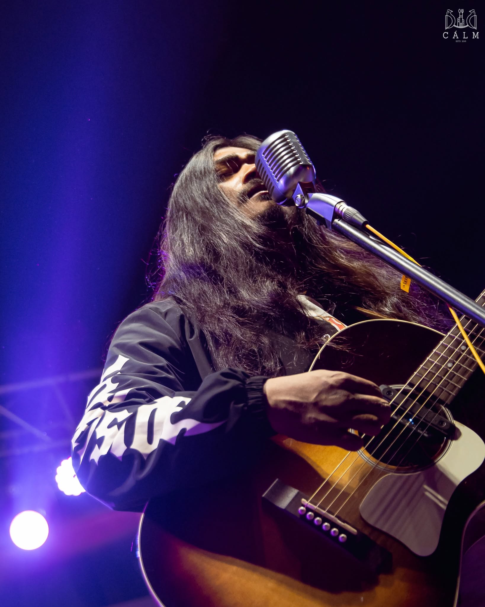 Singer and guitarist performing under purple lights