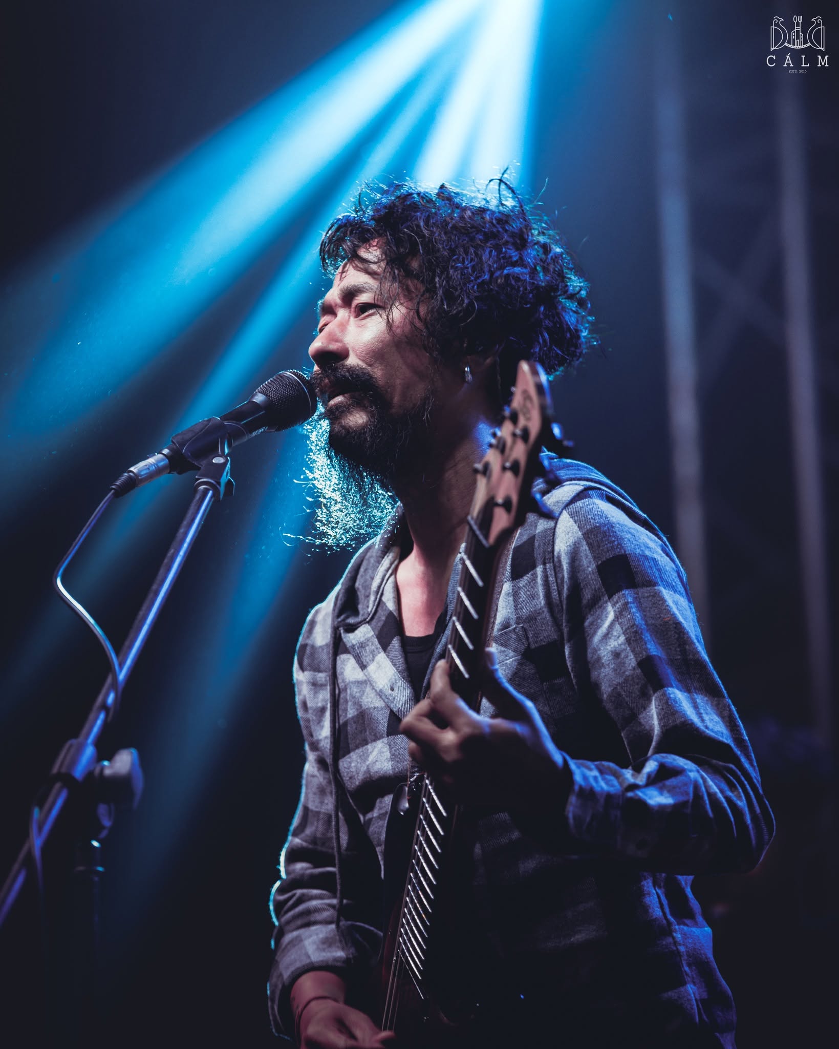 Singer and bassist performing under blue lights